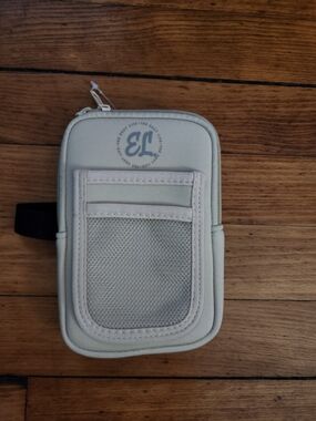 Beige tumbler pouch. Front mesh pocket and slip slots for small items.